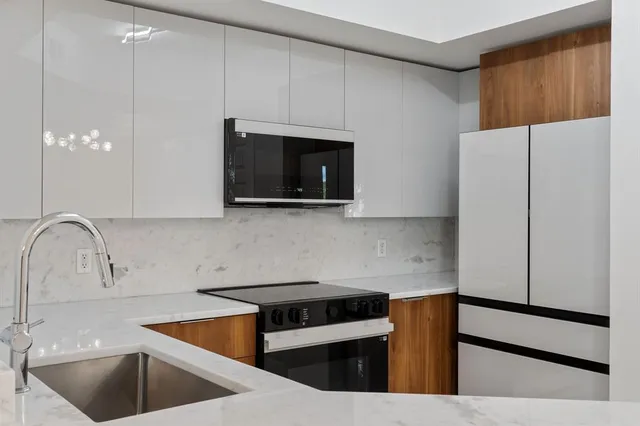 a kitchen with stainless steel appliances a sink a stove a microwave a sink a refrigerator and cabinets