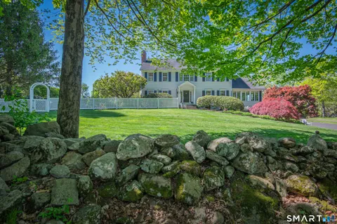 a view of a house with a big yard plants and large trees