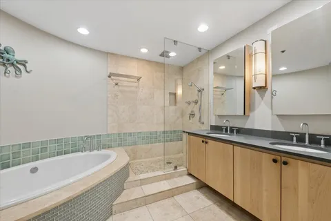 a bathroom with a bathtub a double vanity sink and mirror