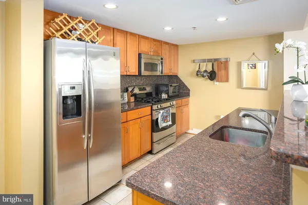 a kitchen with stainless steel appliances granite countertop a refrigerator a stove and a sink with wooden floor