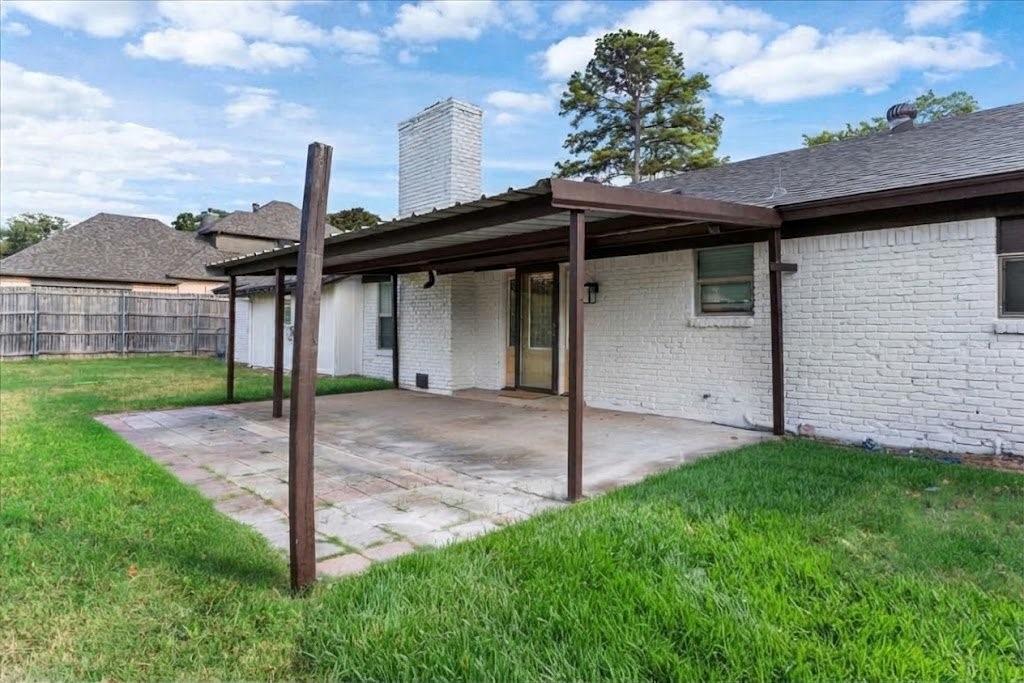 3509 West Sublett Road Arlington, TX 76017 - Photo 34 of 39 Covered patio area with concrete and paver flooring, white brick exterior, and a prominent chimney feature