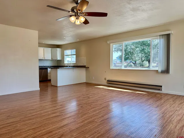 a view of an empty room with window and wooden floor