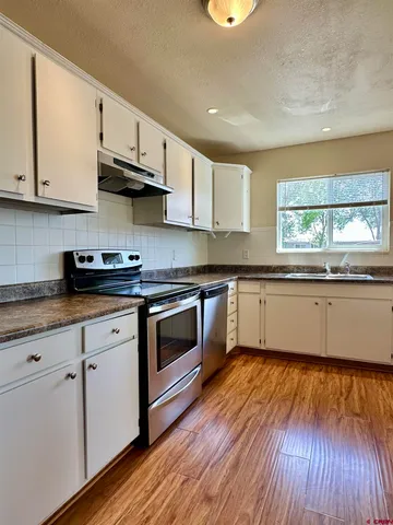 a white kitchen with granite countertop stainless steel appliances