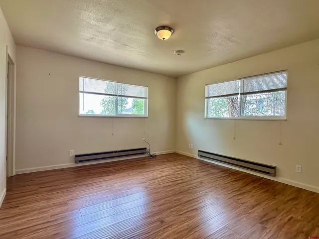 a view of an empty room with wooden floor and a window