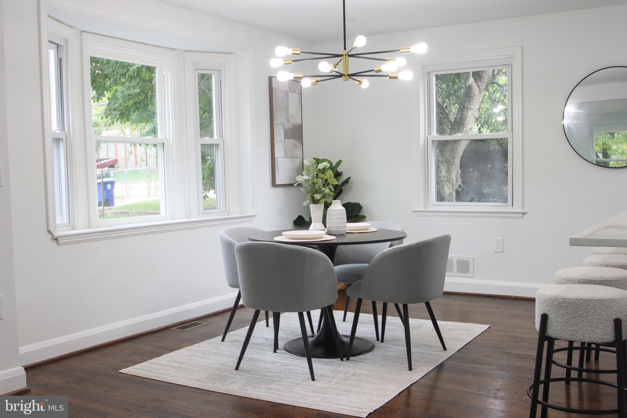 4501 Rokeby Road Baltimore, MD 21229 - Photo 5 of 26 a dining room with wooden floor a chandelier a glass table and chairs