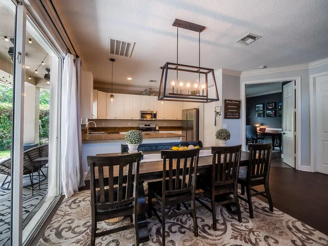 a dining room with wooden floor a chandelier a wooden table and chairs