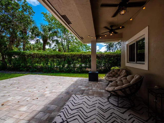 a view of a patio with table and chairs potted plants and floor to ceiling window