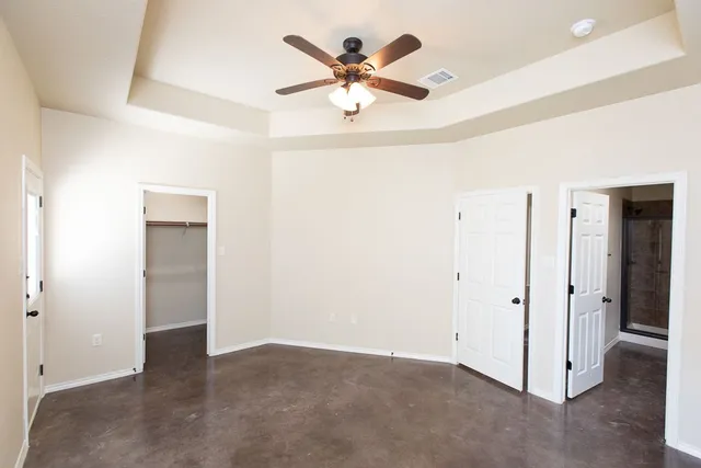 an empty room with chandelier fan and closet