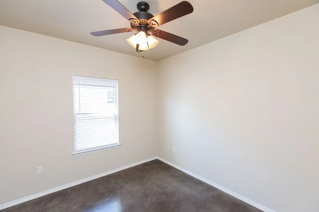 an empty room with a window and a fan