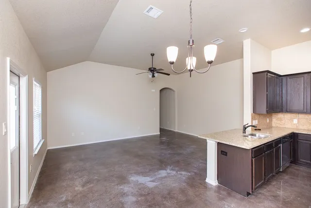 a room with kitchen island stainless steel appliances and chandelier