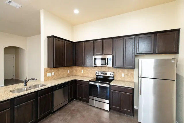 a kitchen with a refrigerator sink and cabinets
