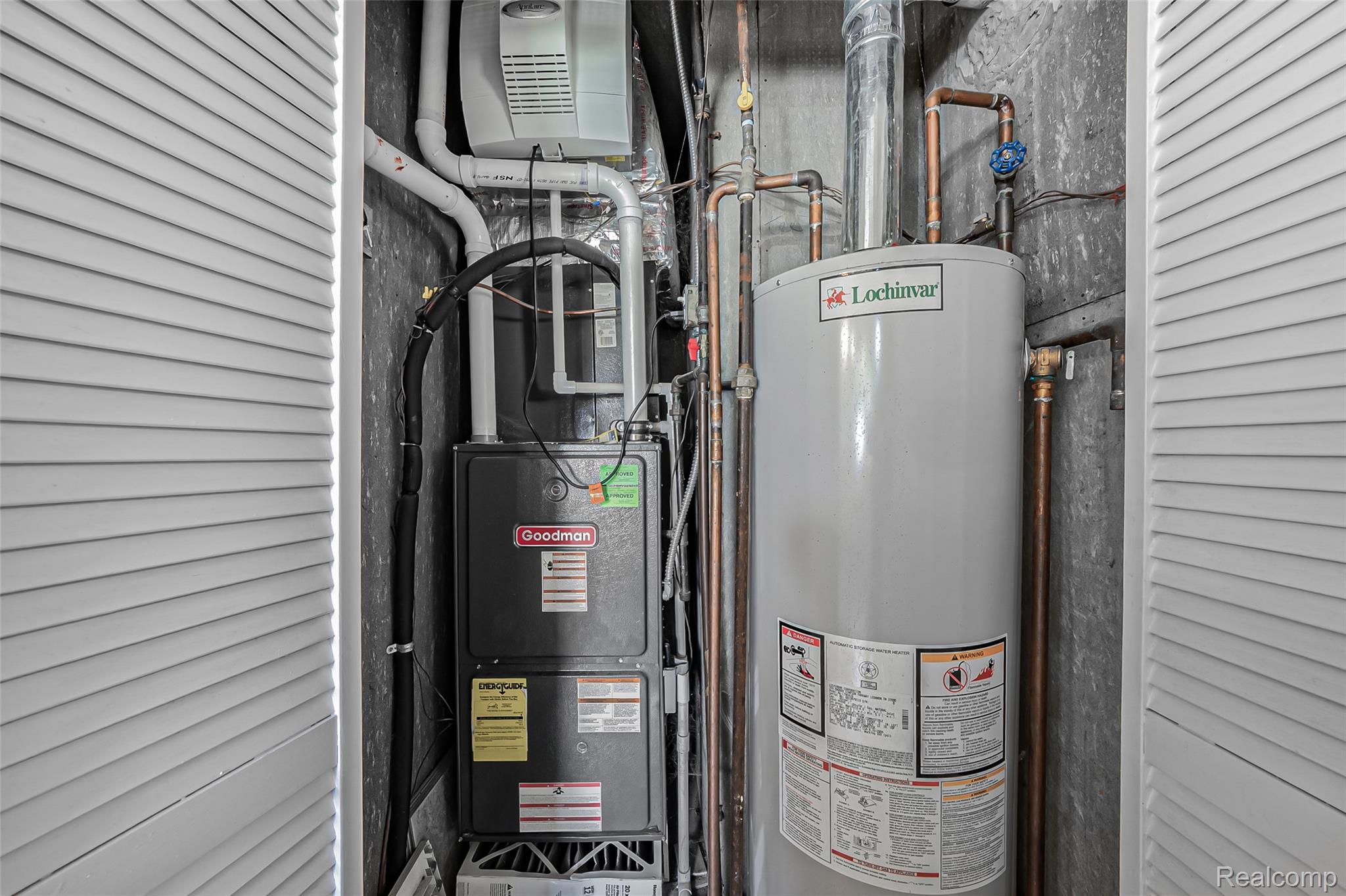 2329 Rutherford Road Bloomfield Hills, MI 48302 - Photo 40 of 46 Enclosed utility closet featuring a Goodman furnace and Lochinvar water heater, with visible copper plumbing and white louvered bifold doors