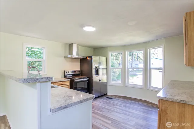 a kitchen that has a microwave a stove white cabinetry and wooden floor
