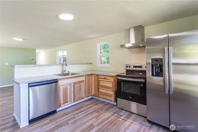 a kitchen with stainless steel appliances granite countertop a refrigerator a stove and a sink