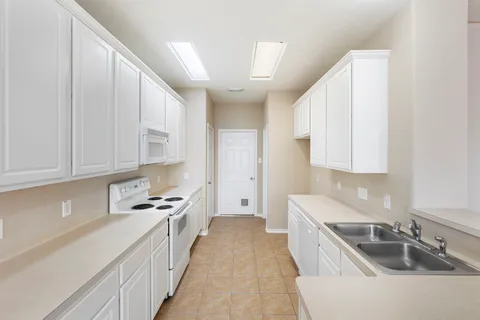 a kitchen with granite countertop a sink stove and cabinets