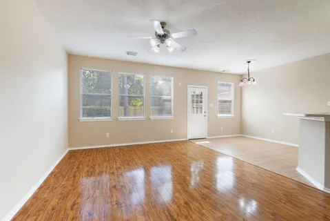 a view of an empty room with wooden floor and a window