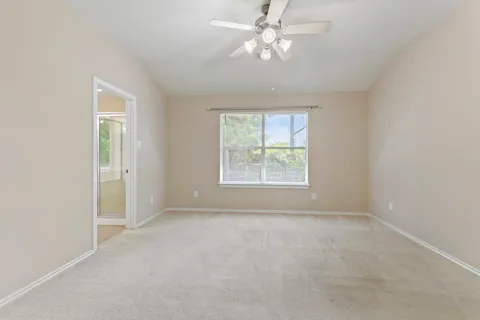 an empty room with a window and a fan