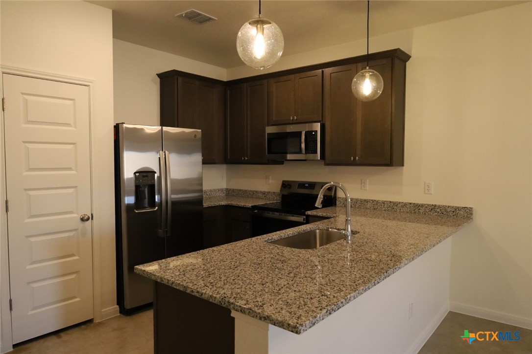 2916 Wildcat Rdg Road, Unit B Temple, TX 76501 - Photo 22 of 39 a kitchen with stainless steel appliances granite countertop a sink a refrigerator and a granite counter tops