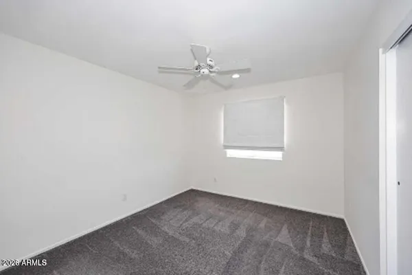 an empty room with windows and ceiling fan