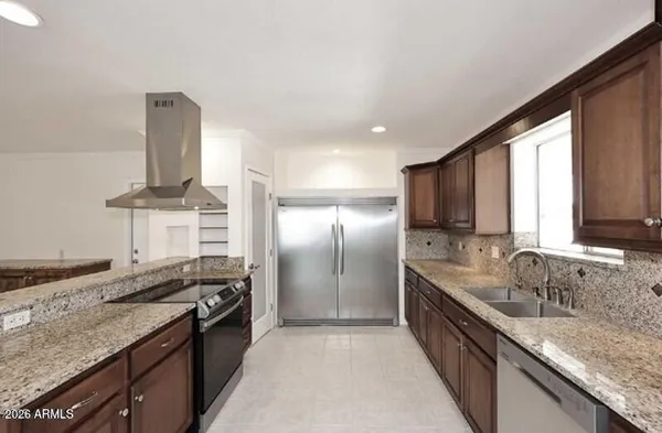 a kitchen with stainless steel appliances kitchen island granite countertop a sink and a refrigerator
