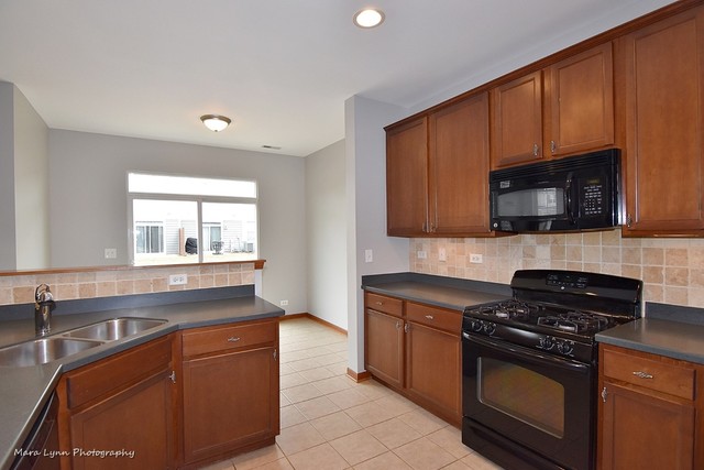 427 Acushnet Street Elgin, IL 60124 - Photo 8 of 26 a kitchen with granite countertop a sink dishwasher stove and microwave with wooden cabinets