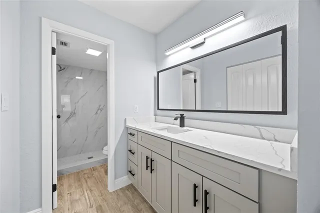a en suite bathroom with a granite countertop sink mirror and double