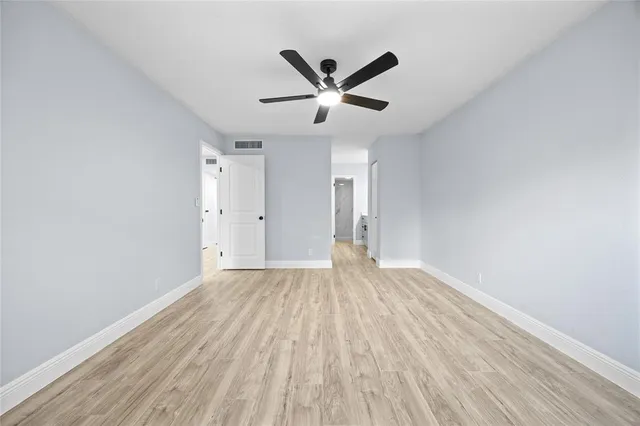 an empty room with wooden floor and a ceiling fan