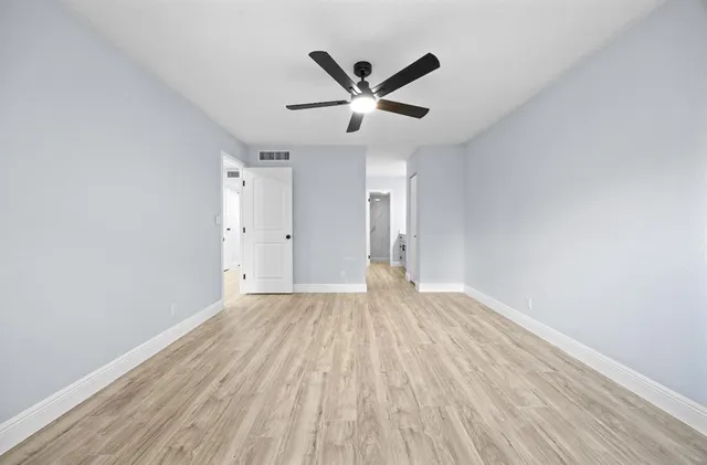 an empty room with wooden floor and a ceiling fan