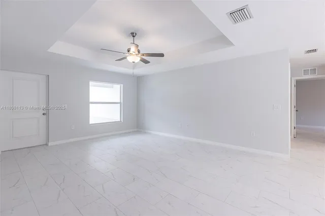 an empty room with windows and chandelier fan