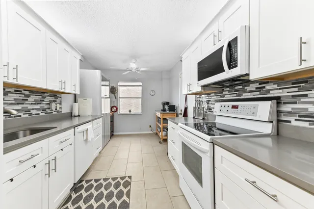 a large kitchen with stainless steel appliances and white cabinets
