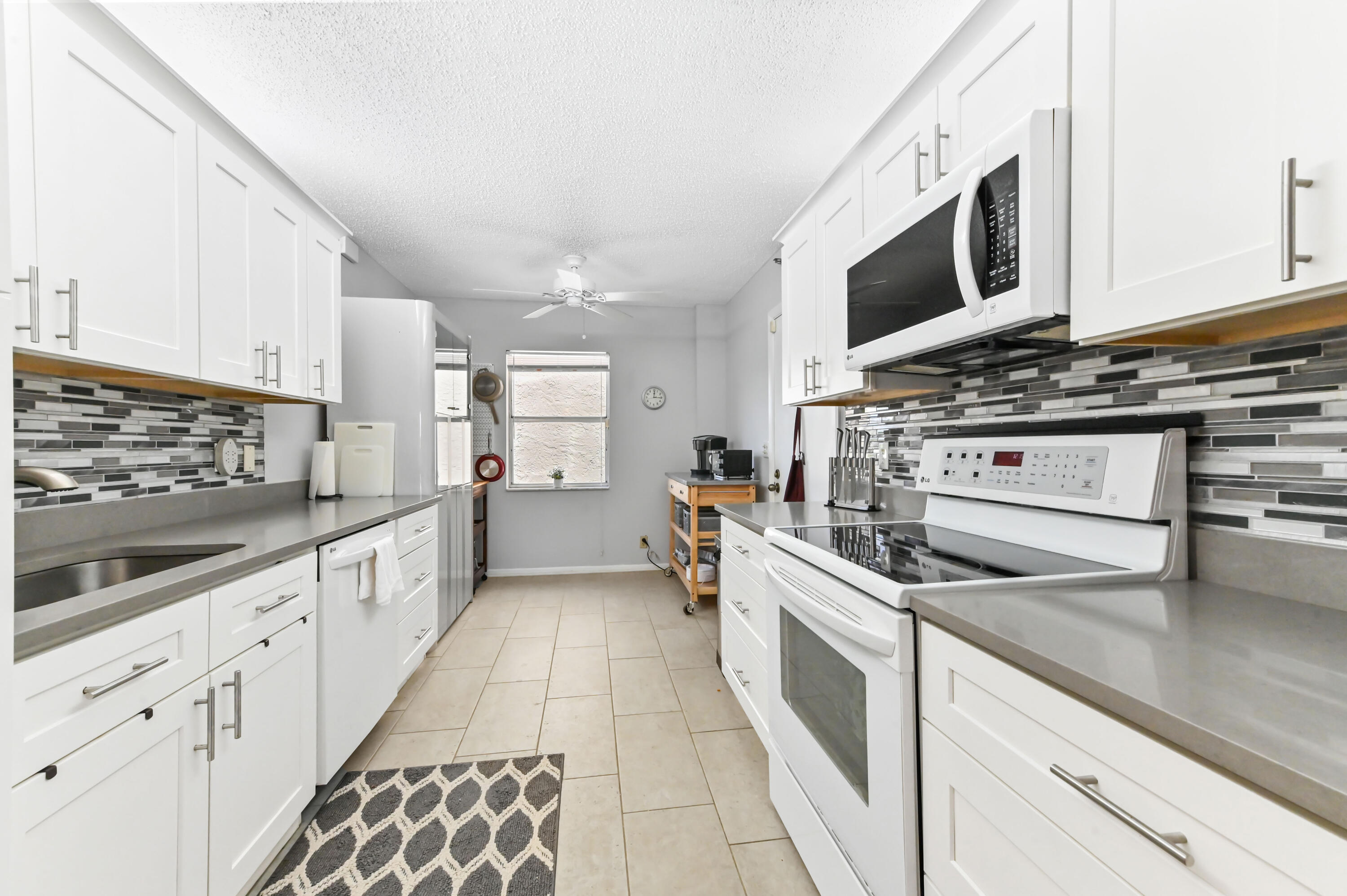 6768 10th Avenue North, Unit 316 Lake Worth, FL 33467 - Photo 12 of 38 a large kitchen with stainless steel appliances and white cabinets