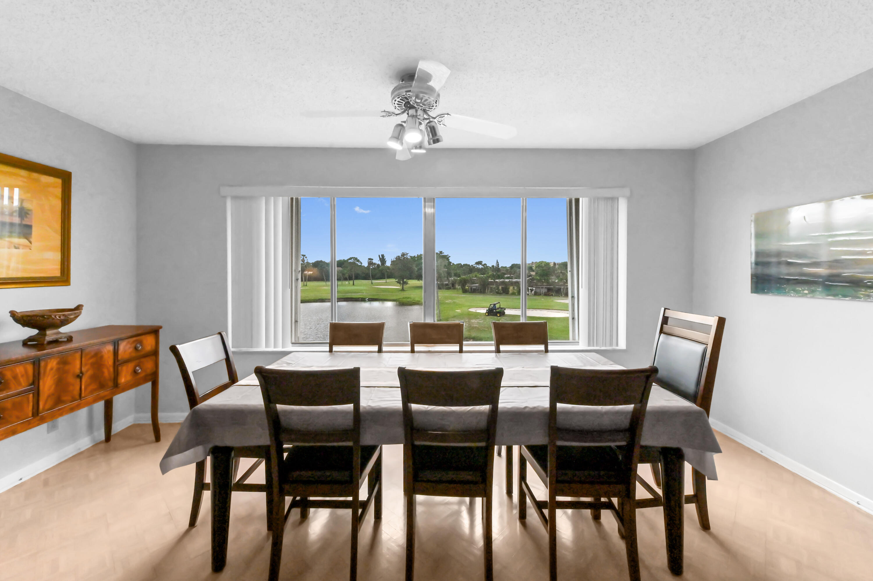 6768 10th Avenue North, Unit 316 Lake Worth, FL 33467 - Photo 4 of 38 a dining room with wooden floor a chandelier a glass table and chairs