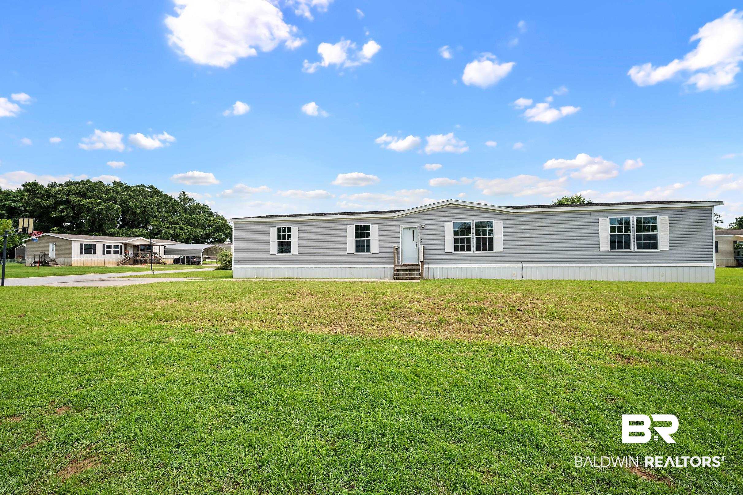 21601 Westside Loop Silverhill, AL 36576 - Photo 9 of 42 Light gray siding exterior with white window trim and shutters, complemented by a dark shingle roof