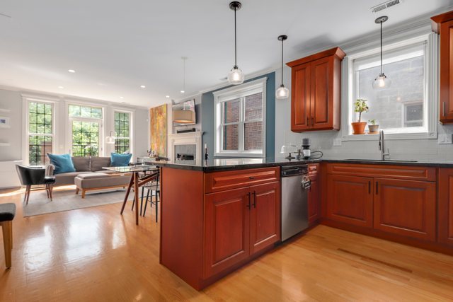 4730 North Malden Street, Unit 3 Chicago, IL 60640 - Photo 3 of 25 a open kitchen with granite countertop a stove top oven a sink dishwasher a dining table and chairs with wooden floor