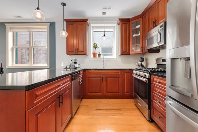 4730 North Malden Street, Unit 3 Chicago, IL 60640 - Photo 4 of 25 a kitchen with stainless steel appliances granite countertop wooden cabinets a sink and dishwasher