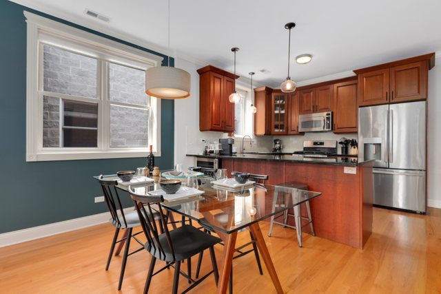 4730 North Malden Street, Unit 3 Chicago, IL 60640 - Photo 5 of 25 a kitchen with stainless steel appliances wooden floor dining table and chairs