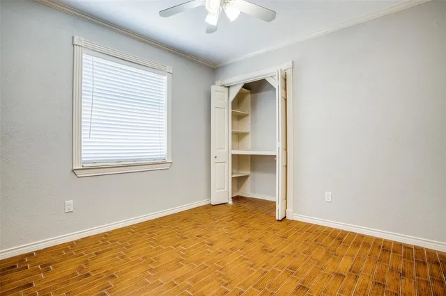 a view of empty room with wooden floor and fan