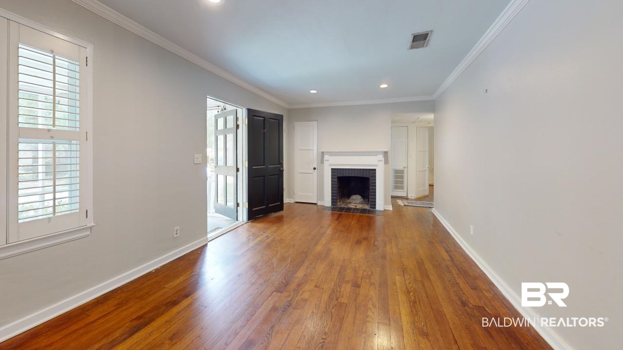 48 Hathaway Road West Mobile, AL 36608 - Photo 3 of 40 Unfurnished living room featuring a fireplace, crown molding, wood-type flooring, and a healthy amount of sunlight