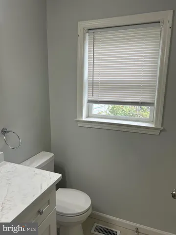 a white toilet sitting next to a window in a bathroom