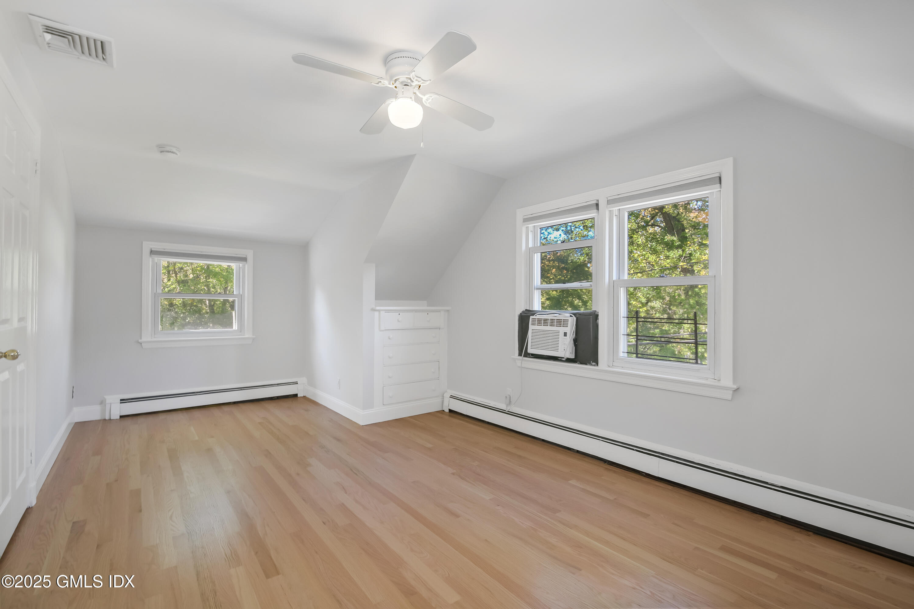 84 Indian Field Road Greenwich, CT 06830 - Photo 25 of 40 an empty room with wooden floor ceiling fan and windows