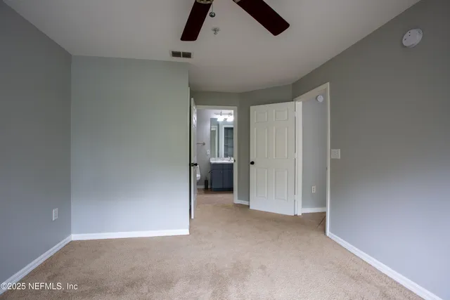 an empty room with chandelier fan and windows