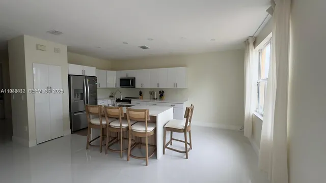 a view of a dining room with furniture and a refrigerator