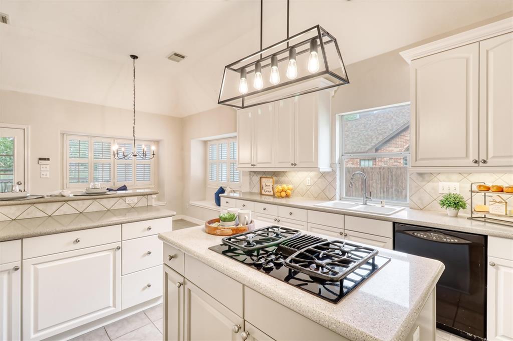 a kitchen with stainless steel appliances granite countertop a sink stove and white cabinets next to a window