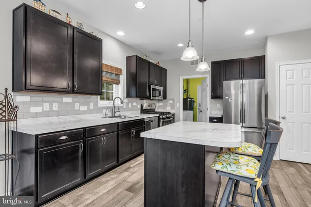 a kitchen with stainless steel appliances granite countertop wooden cabinets a stove a kitchen island and chairs