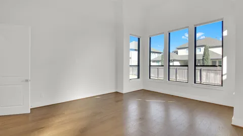 a view of an empty room with a window and wooden floor