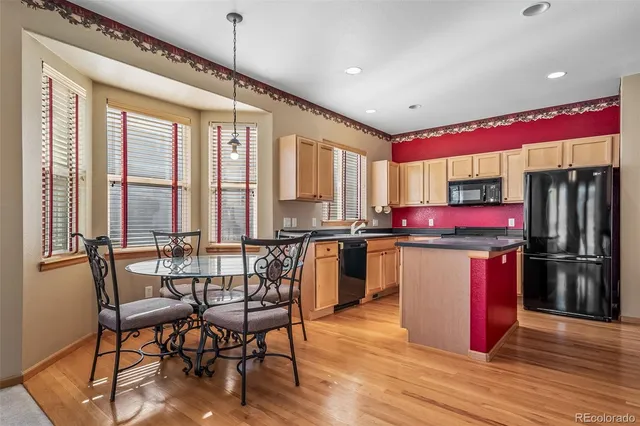 a kitchen with stainless steel appliances granite countertop a stove top oven a sink dishwasher a dining table and chairs with wooden floor