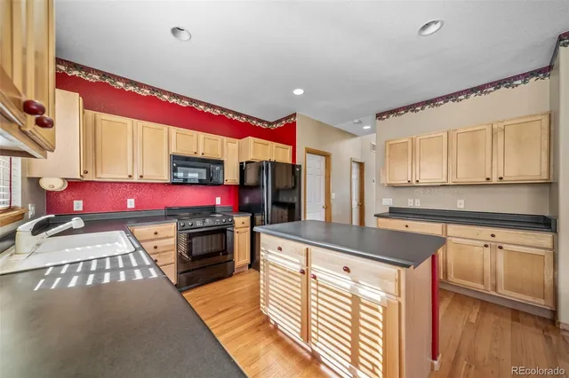 a kitchen with red cabinets and wooden floor