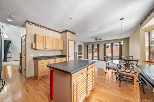 a very nice looking kitchen with granite countertop a stove a sink a dining table and chairs with wooden floor