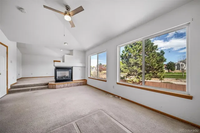 an empty room with fireplace fan and windows