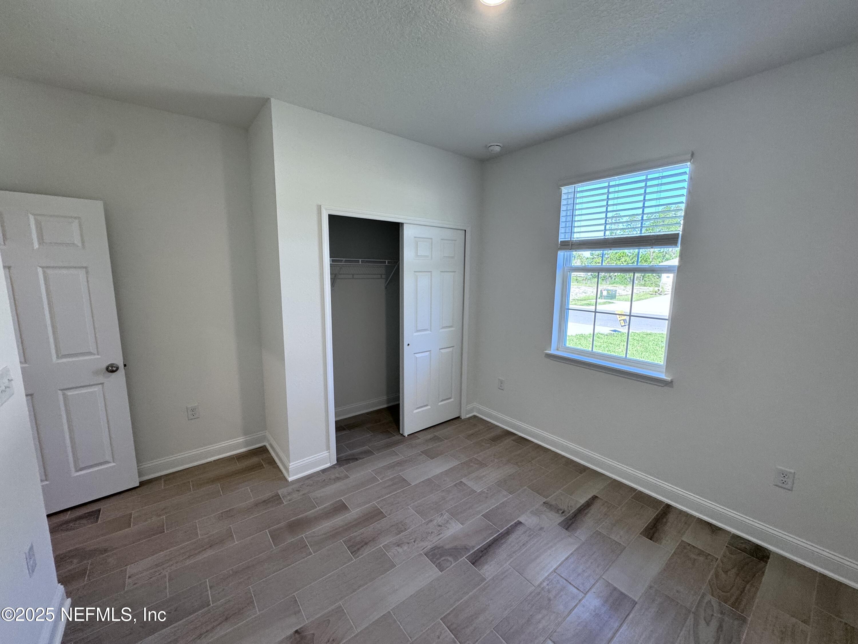 11156 Spg Mdws Road Jacksonville, FL 32222 - Photo 27 of 33 an empty room with wooden floor and windows